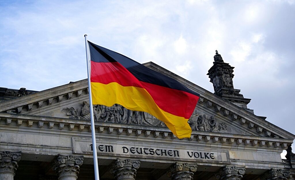 GERMAN LANGUAGE CLASSES NEAR ME (WESTERN MORGEN GERMAN LANGUAGE SCHOOL) 1 German national flag waving in front of the Reichstag building in Berlin, a symbol of democracy.