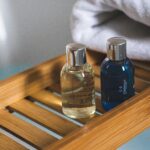 Two elegant toiletries bottles on a bamboo tray in a serene bathroom setting.Salon Salon
