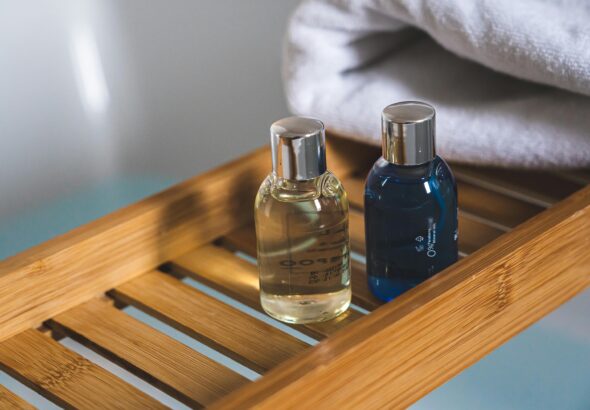 Two elegant toiletries bottles on a bamboo tray in a serene bathroom setting.Salon Salon